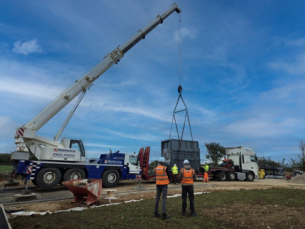 Large crane installing a human cremation system at a modern crematorium with blue sky